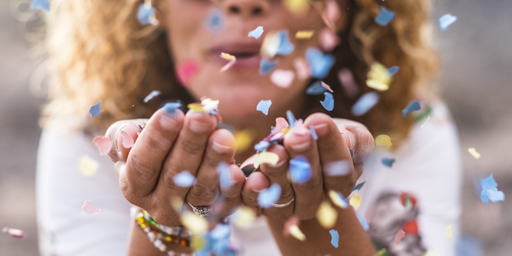 Woman blowing confetti toward you.