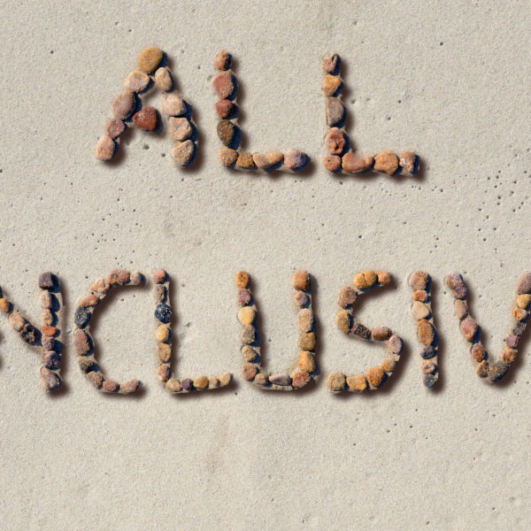 Rocks lined up on a beach spelling out "All Inclusive"