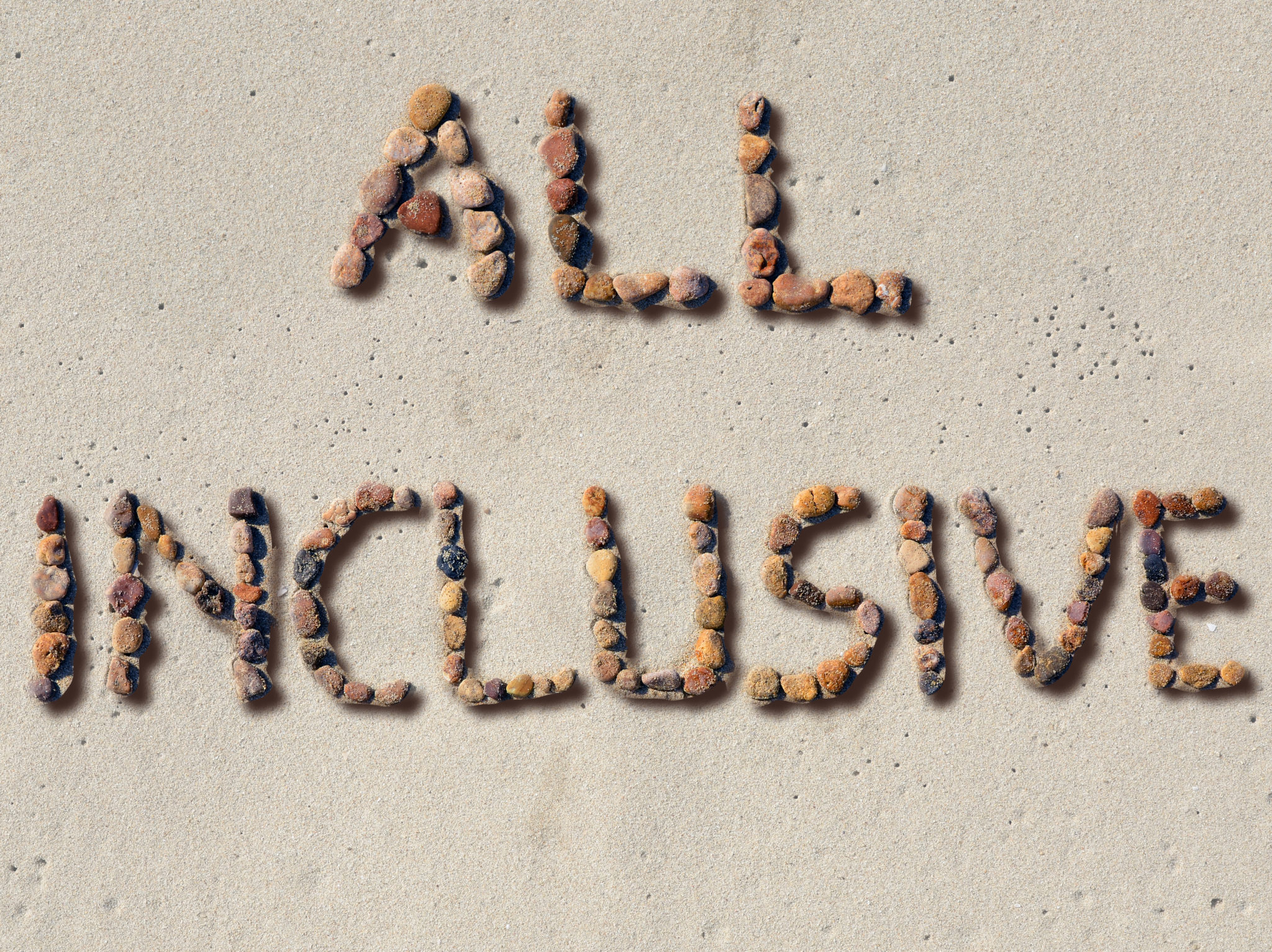 Rocks lined up on a beach spelling out "All Inclusive"