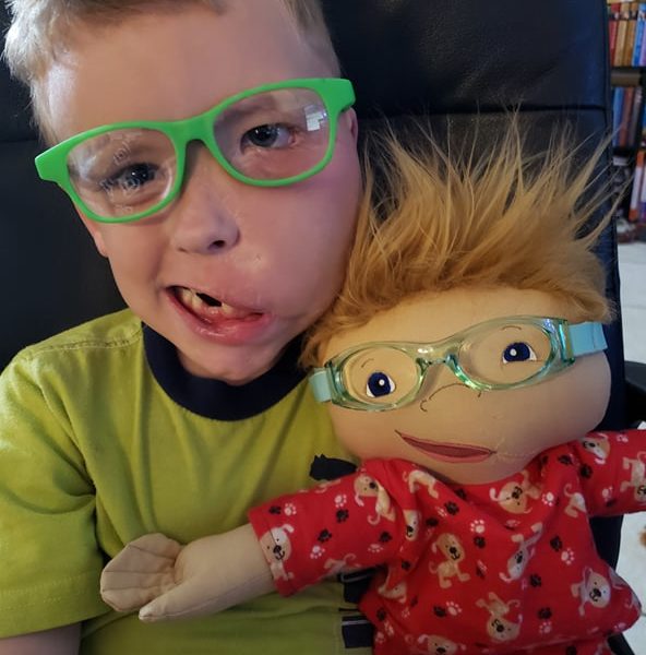 excited child holding a doll with a matching crooked smile and glasses