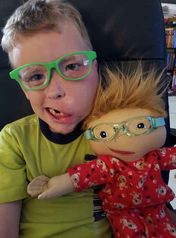 excited child holding a doll with a matching crooked smile and glasses