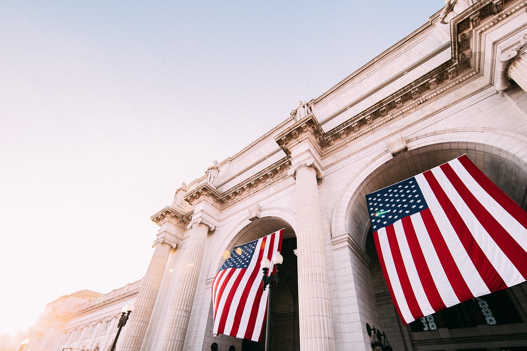 Official building with two American flags hanging inside of arches